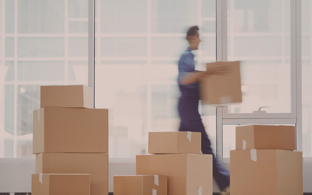 Professioneller Büroumzug in Rosenheim: Ein Mitarbeiter transportiert Umzugskartons in einem neuen, modernen Bürogebäude.